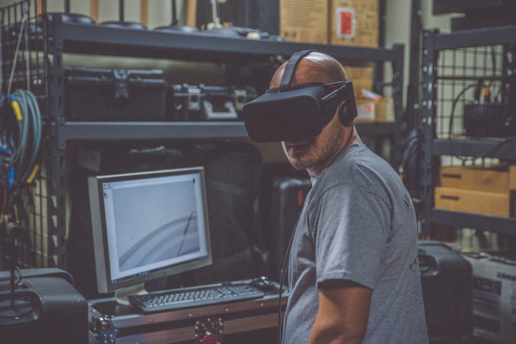 A man in front of his personal computer using VR goggles